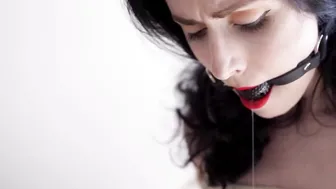 Fully nude dark haired with a gag into her mouth bound with ropes