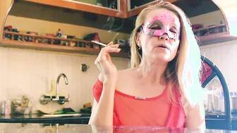 Irresistible sexy Blonde cougar into Red Dress With Party Mask Smoking Cigarette