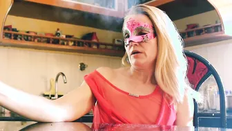Irresistible sexy Blonde cougar into Red Dress With Party Mask Smoking Cigarette