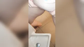 Pee into a urinal into a guyss outdoor restroom